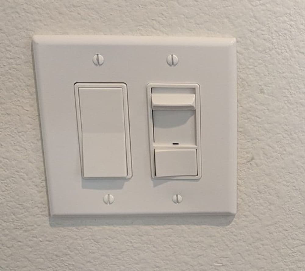 Two light switches on a white wall plate, one toggle and one dimmer switch.