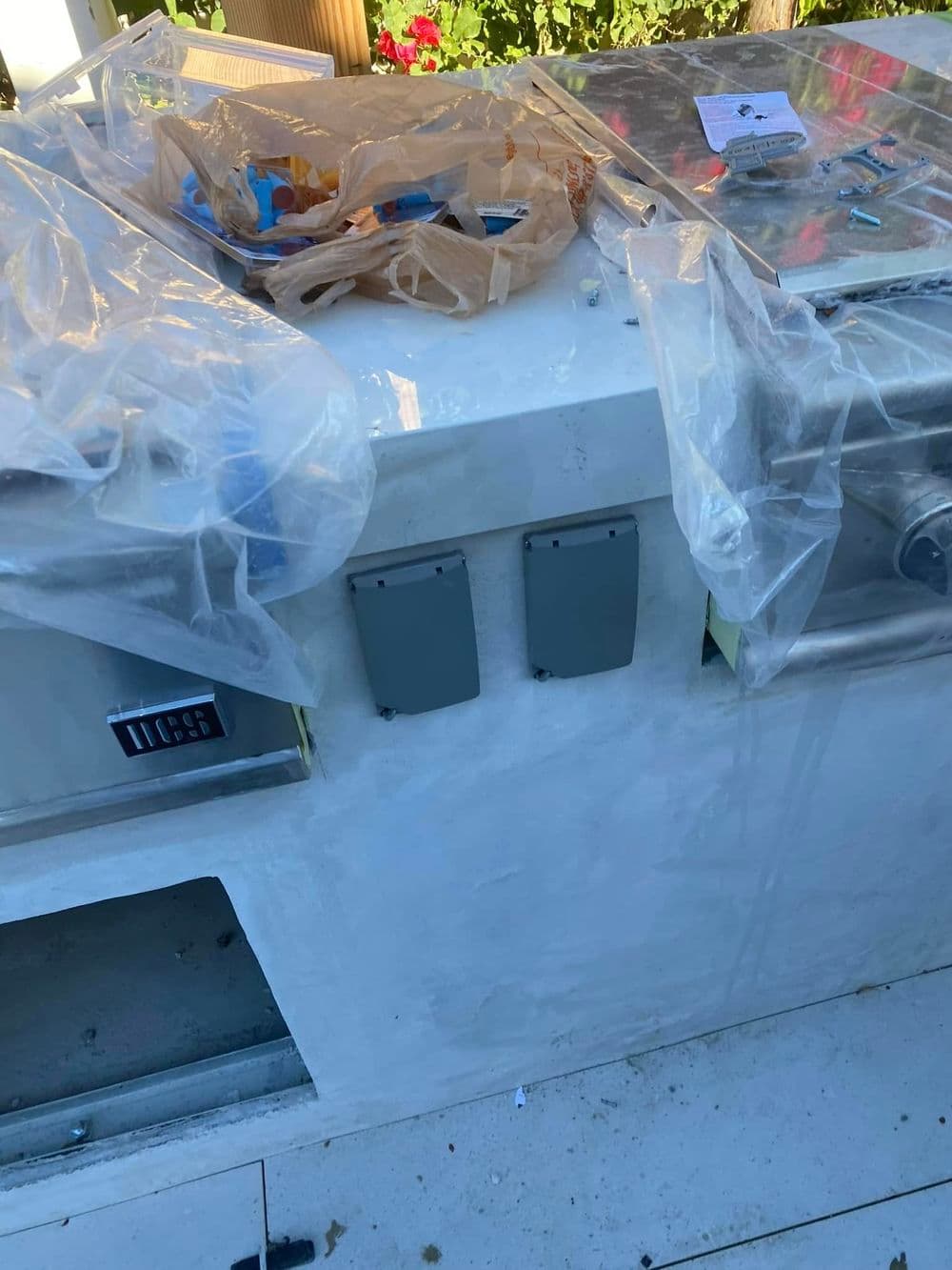 Work in progress on a stone countertop with tools and plastic coverings outdoors.