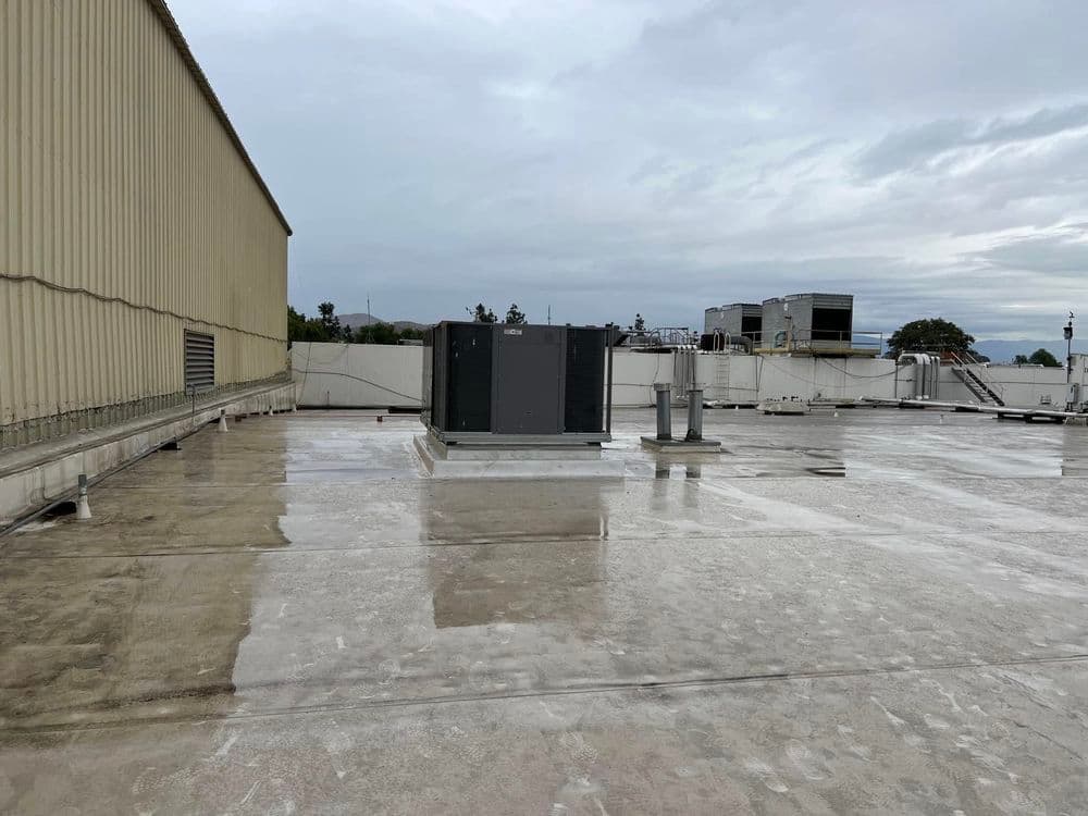 HVAC unit installed on a commercial building rooftop with cloudy sky backdrop.