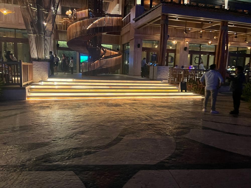 Illuminated staircase with spiral design leads to a restaurant entrance at night.