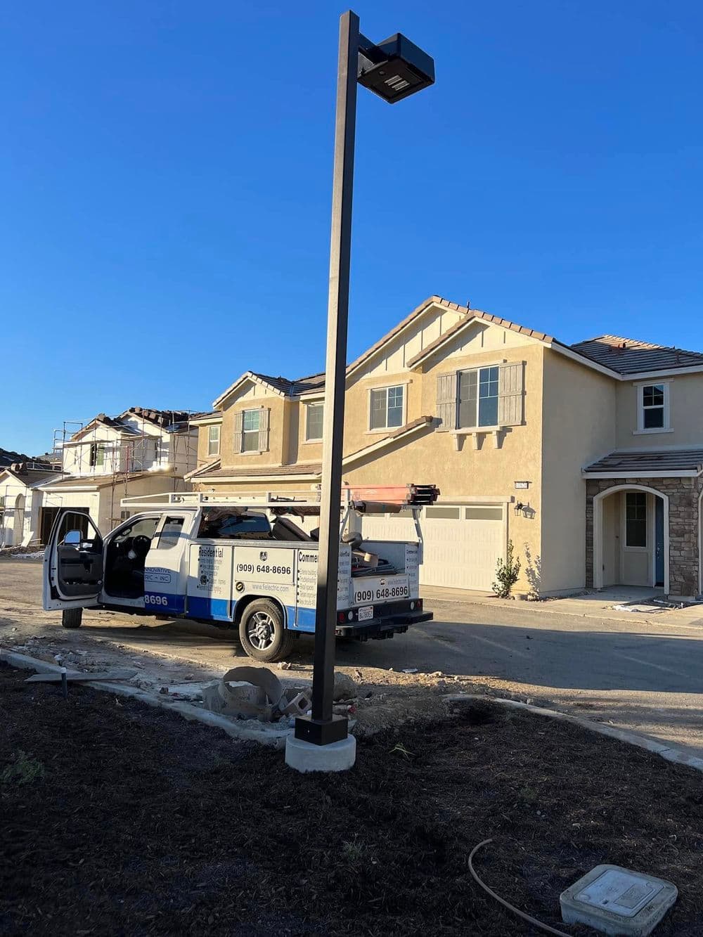 Service van parked near new residential construction with streetlight.